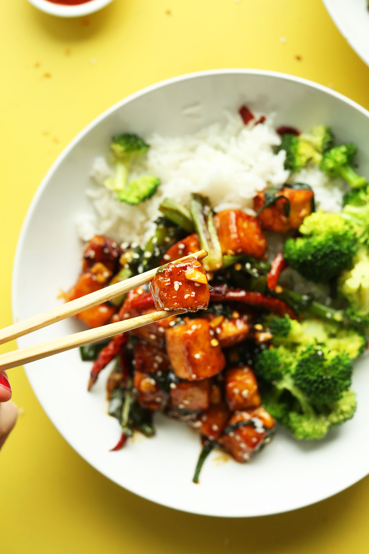 Using chopsticks to pick up a piece of our delicious General Tso's Tofu