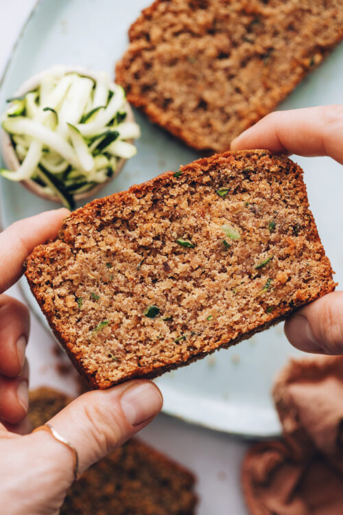Holding up a slice of gluten-free zucchini bread to show the crumb texture